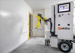 Okibos målarrobot i arbete. Den mobila plattformen använder sensorer och AI för att anpassa sprutmönstret och kan måla upp till 1 500 kvadratmeter per dag med jämn finish.